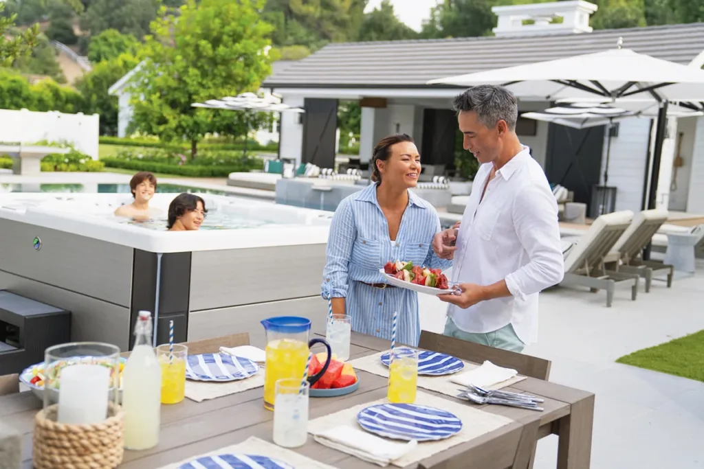 A family having brunch in their backyard and relaxing in their Hot Spring Highlife hot tub