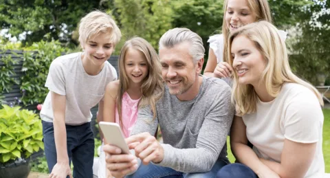 A family using the Virtual View™ AR virtual hot tub shopping app on a smartphone, virtually showing how a Hot Springs Spa would look in a backyard using virtual reality technology.