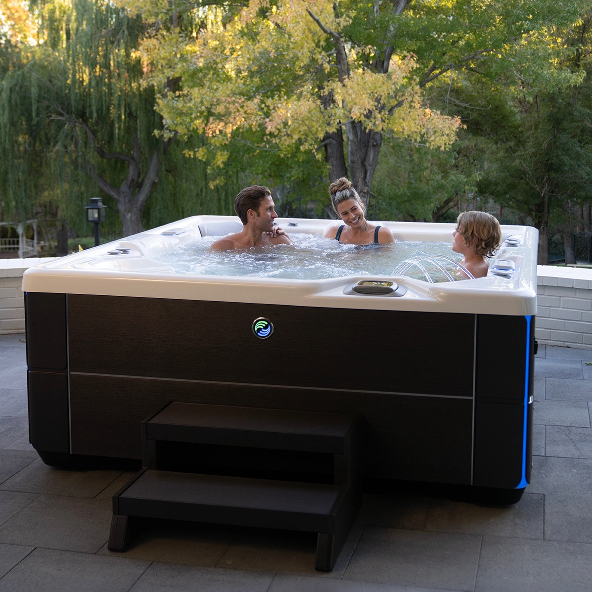 A family of three, mother, father, and young son, enjoying a hot tub soak in their Hot Spring Highlife Vanguard hot tub